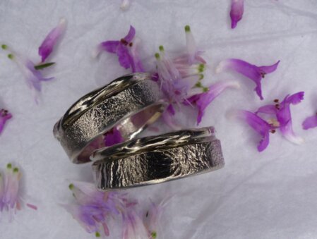 Auffallende Eheringe mit besonderem Design: Auf eine Ringschiene aus Silber habe ich alte, aufgearbeitete Ringe aus Weissgold als tordiertes Band aufgeloetet. Ein tolles Beispiel für Upcycling! Breite 6-7 mm. 925er Silber und 585er Weissgold.